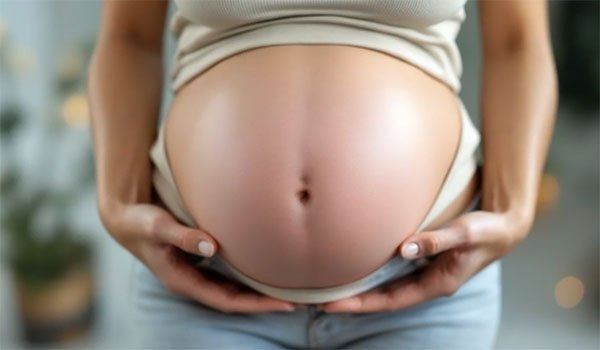 Close-up of a pregnant belly with hands gently holding it.