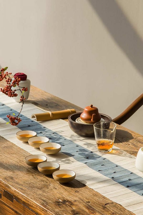 Traditional tea setup with clay teapot and cups on a rustic table.