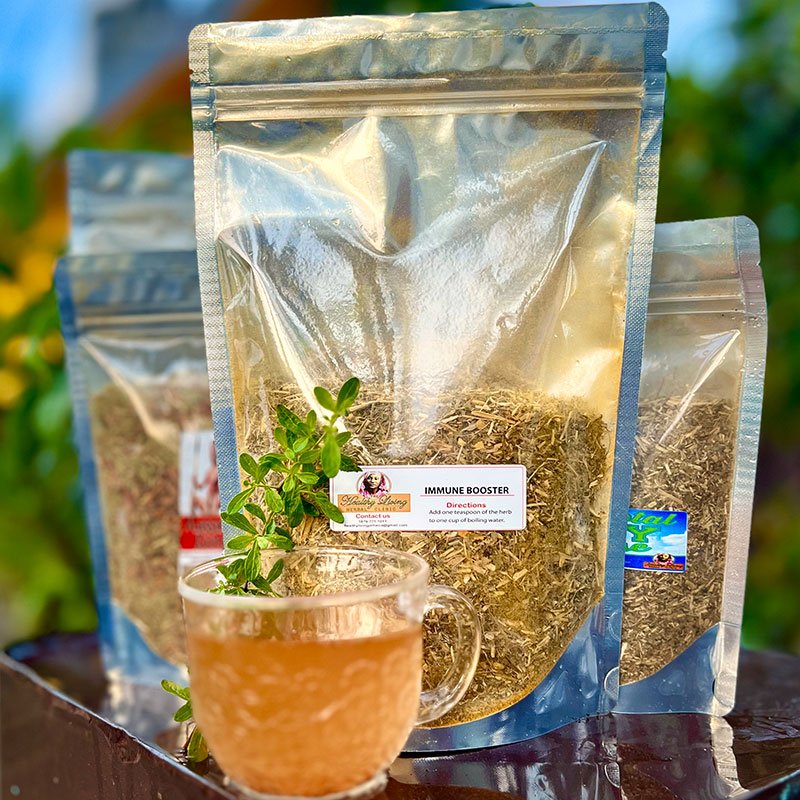 Three silver bags of herbal tea with a glass cup of brewed tea and herbs.