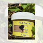 Small jar of natural hair tonic with plant background.